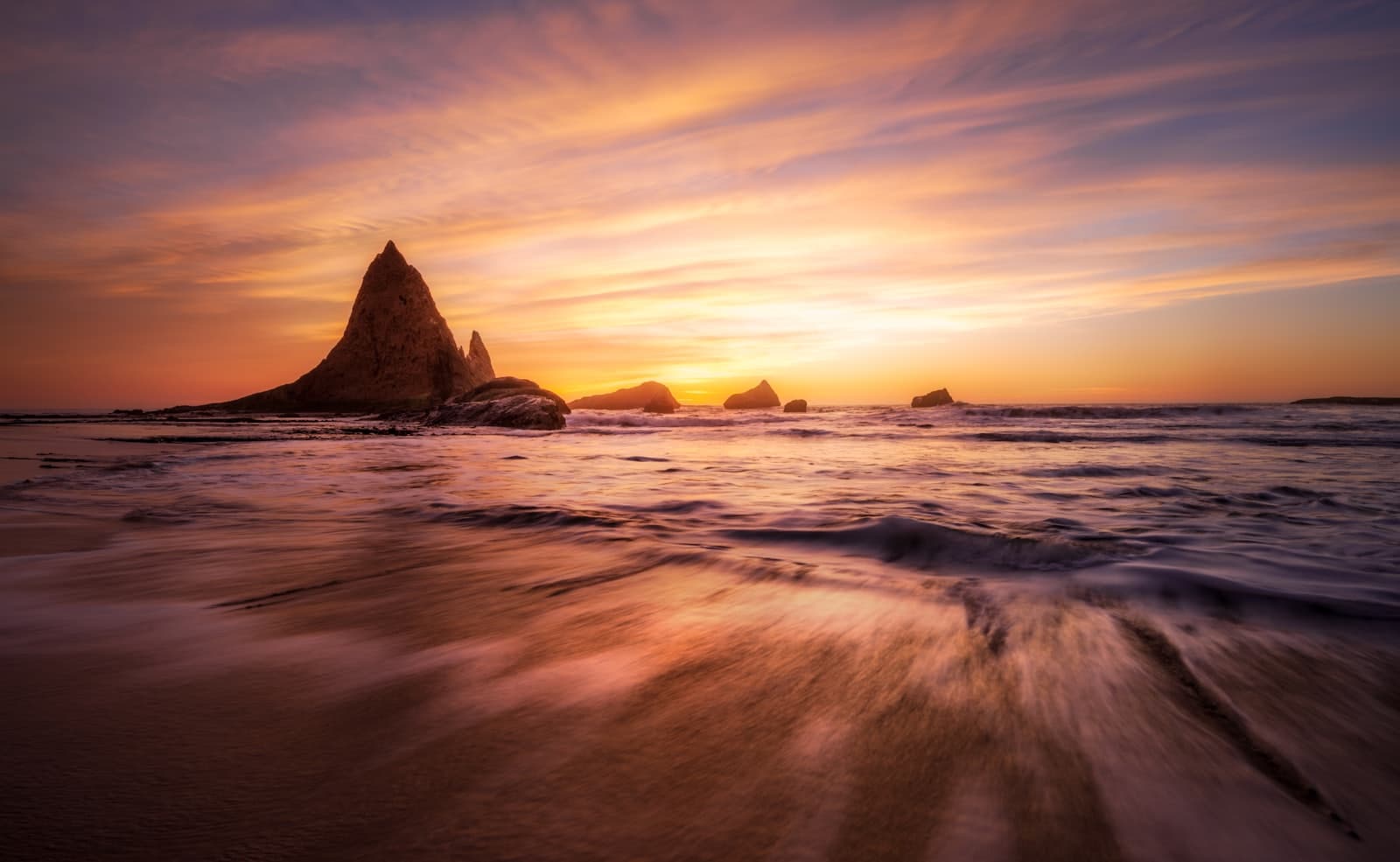 Dramatic sunset over a rocky coastline with ocean waves